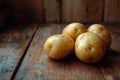 Four raw potatoes sit on a weathered wooden table, ready for cooking Royalty Free Stock Photo