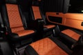 Four rear seats in a minibus are deployed to each other and tightened in black and brown leather with a diamond-shaped stitching