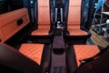 Four rear seats in a minibus are deployed to each other and tightened in black and brown leather with a diamond-shaped stitching