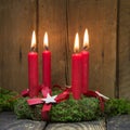 Four red burning advent candles on a wreath.