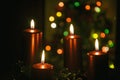 Four red candles burning on advent wreath with blurred colorful christmas tree with glowing lights in the background on evening Royalty Free Stock Photo