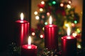 Four red candles burning on advent wreath with blurred colorful christmas tree with glowing lights in the background on evening Royalty Free Stock Photo