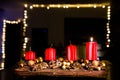 Four red candles - the first lighted candle of the first Sunday of Advent festival before Christmas with lightning chain in backgr