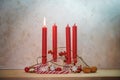 Four red candles, one is lit for the first Sunday before Christmas, Advent decoration on a wooden table against a rustic wall,