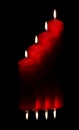 Four red candles reflected on dark background