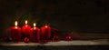 Four red candles, three of them burning on the third advent, christmas decoration with spruce twigs and baubles on a rustic board Royalty Free Stock Photo