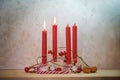 Four red candles, two are lit for the second Sunday before Christmas, Advent decoration on a wooden table against a rustic wall,