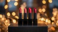Four red lipsticks arranged on a black surface. The background features soft, blurred lights creating a festive atmosphere Royalty Free Stock Photo