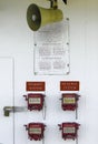 Four red valve release boxes are mounted on a white wall with an announcement speaker Royalty Free Stock Photo