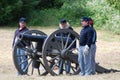 Four reenactors standing by a Civil War cannon.