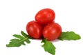 Four ripe tomatoes stacked in a heap. Water droplets glisten on the peel. Green leaves lie under the tomatoes Royalty Free Stock Photo