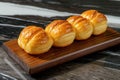 Four rolls of bread sit on a wooden board atop a marble counter. Royalty Free Stock Photo