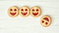 Four round biscuits smiling faces, one of them falls down