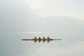 Four rowers on boat floating on sunny morning on background of mountains on lake of Lugano. Royalty Free Stock Photo