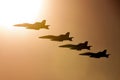 Four Royal Australian Air Force RAAF Boeing F/A-18F Super Hornet multirole fighter aircraft flying in formation at sunset.