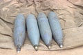 Four rusty artillery shells on sand