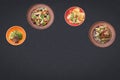 Four salads on a black background lie in a semicircle with sopy space