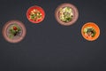 Four salads on a black background lie in a semicircle with sopy space