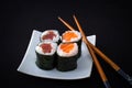 Four salmon, tuna maki sushi and chopstick on black Royalty Free Stock Photo