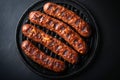 Four sausages are cooking on a grill pan on a black surface Royalty Free Stock Photo