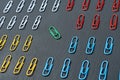 Four sections of rows of paper clips for office work or education and one green color in center lies on dark scratched concrete ta