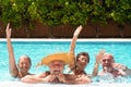 Four senior people friends laughing enjoying the swimming pool together. Bright sunlight and transparent water. Large smiles and Royalty Free Stock Photo