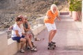 Four seniors together at the park having fun - group of three people sitted on a bench or wall looking at man pensioner trying to