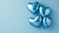 Four shiny blue heart shaped balloons floating on a light blue background with copy space.