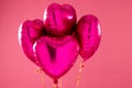 Four shiny pink heart shaped balloons floating on pink background with copy space