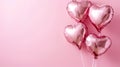 Four shiny pink heart-shaped balloons floating on on pastel pink background with copy space.