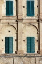 Four shuttered windows in a geometric brick wall