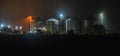 Four silos for bulk materials in a farm or factory at night, illuminated by lanterns. Farm or plant at night. Royalty Free Stock Photo