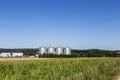 Four silver silos in field under blue sky