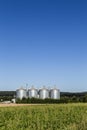 Four silver silos in field under blue sky