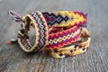 Four simple handmade homemade natural woven bracelets of friendship on wooden background, rainbow colors