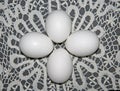 Four simple white eggs lie on a Lacy background. Pure white eggs are laid on white vintage lace. Group of white eggs. Composition