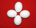 Four simple white eggs on a red background. On a red napkin are clean white eggs. Group of white eggs. White egg.