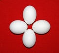 Four simple white eggs lie on a red background. On a bright red towel are pure white eggs. Group of white eggs. Composition of egg