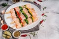 Four skewers with four pieces of chicken fillet with zucchini vegetables and bell peppers on a white plate on a light background Royalty Free Stock Photo