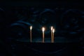 Four slender candles burn brightly in a dimly lit setting, surrounded by darkness. Royalty Free Stock Photo