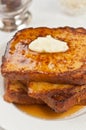 Four slices of freshly baked, homemade french toast with butter and maple syrup