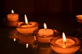 Four small candlesticks with burning even flame candles on a smooth surface Royalty Free Stock Photo