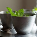 Four small pewter glasses filled with mint julep cocktails. Spearmint garnish.