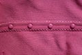 Four small red plastic buttons on the woolen fabric