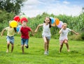 Four smiling kids running on green lawn