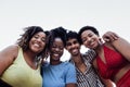 Four smiling mixed race friends standing and looking down at camera. Group of cheerful multiethnic people in casual clothes having Royalty Free Stock Photo