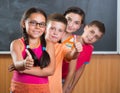 Four smiling schoolchildren standing in classroom