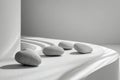 Four smooth round stones arranged on white gently curved layered surface with soft natural light and shadows creating calm Royalty Free Stock Photo