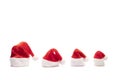 Four souvenir isolated caps with bells lowered. Set of red Santa Claus hats. Family New Year and Christmas holidays. Copy space on Royalty Free Stock Photo