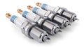 Four spark plugs arranged in a row on a white background Royalty Free Stock Photo